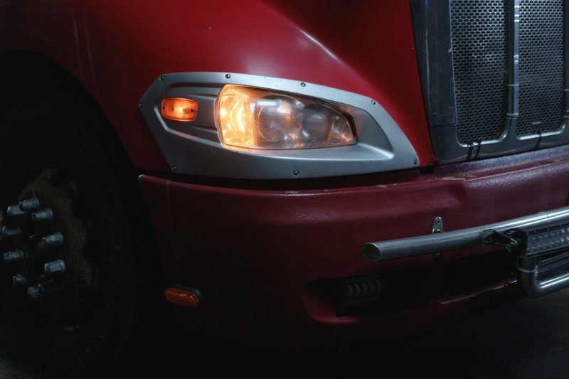 Amber marker lamp and headlight on the front corner of a heavy truck at night.
